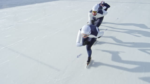 Sportlerinnen-in-Rennanzügen-auf-Eisbahn-Schlittschuh-laufen