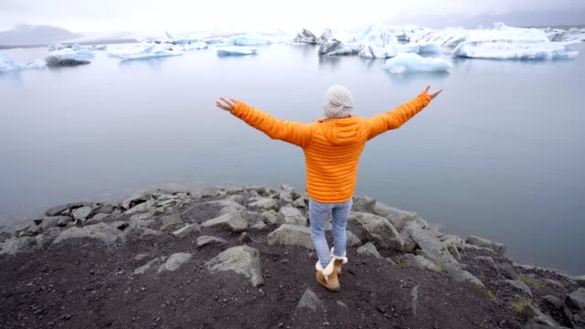 Junge-Frau-Arme-ausgestreckt-an-die-Gletscherlagune-Islands-genießen-Freiheit-in-der-Natur