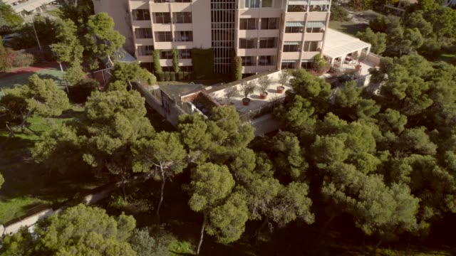 Vista-aérea-de-un-edificio-residencial,-rodeado-de-árboles-en-Grecia.