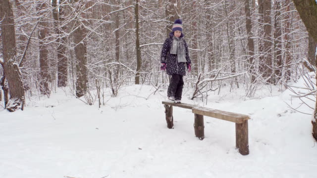 Niña-en-un-banco-de-madera-en-el-bosque-de-invierno-4K