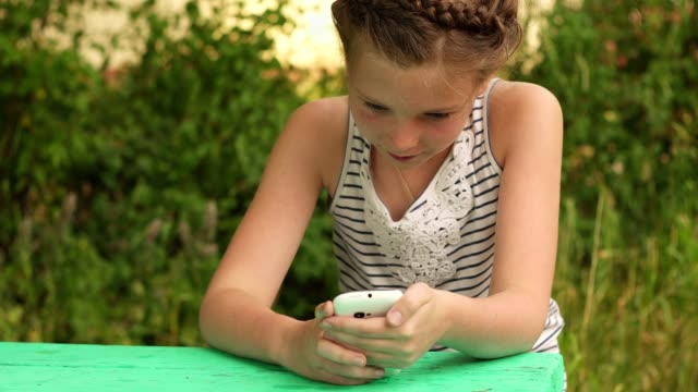 betreffenden-sitzendes-Mädchen-suchen-in-Smartphone-auf-Natur-Hintergründe