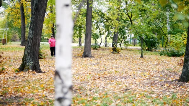 Dos-ancianas-están-haciendo-a-escandinavo-caminando-en-el-parque.-Temporada-de-otoño