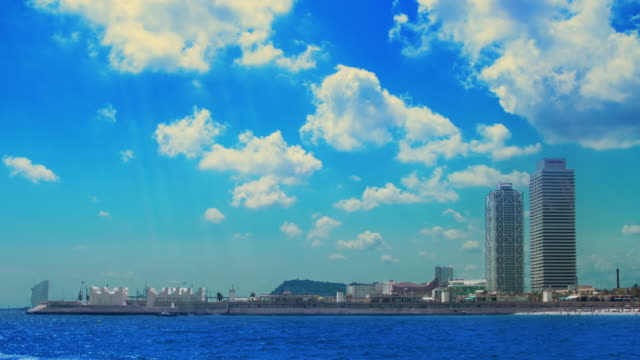 Clouds-over-skyscrapers-on-sea-coast.-Timelapse-of-white-clouds-over-blue-sea