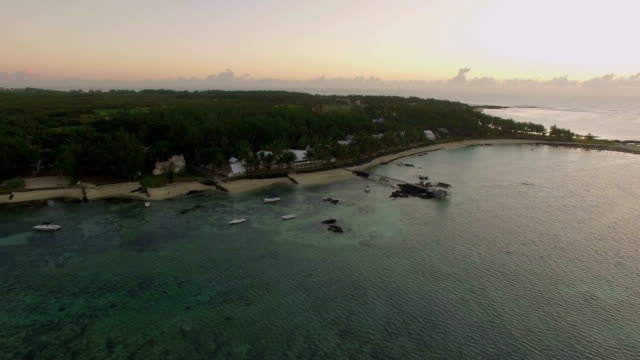 Vista-aérea-de-agua-azul-de-océano-con-olas,-corales-y-plantas-de-agua,-cámara,-hacia-la-costa,-Isla-Mauricio