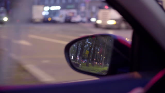 Vista-del-tráfico-de-la-ciudad-en-el-espejo-de-rearview-del-coche