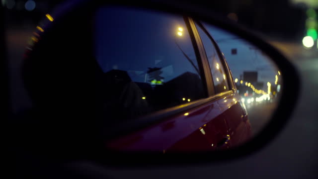 Vista-del-tráfico-de-la-ciudad-en-el-espejo-de-rearview-del-coche
