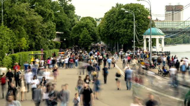 crowds-of-people-walk-along-the-embankment-of-a-city-river,-time-lapse