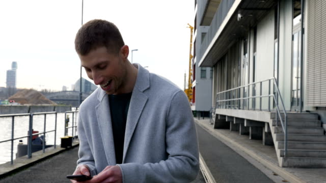 Happy-Man-Using-Mobile-Phone-Standing-at-an-Industrial-Pier