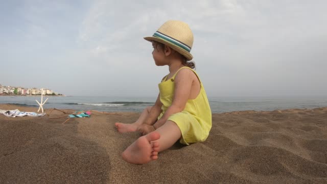 Niedliche-Mädchen-spielen-mit-Sand-am-tropischen-Strand