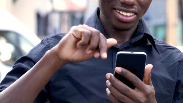 africano-negro-sonriente-con-smartphone-en-la-ciudad---slow-motion