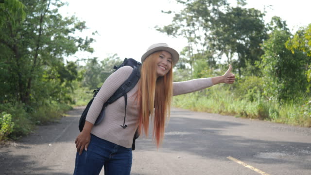 Traveler-woman-backpacker-hitchhiking-on-the-road-and-walking.