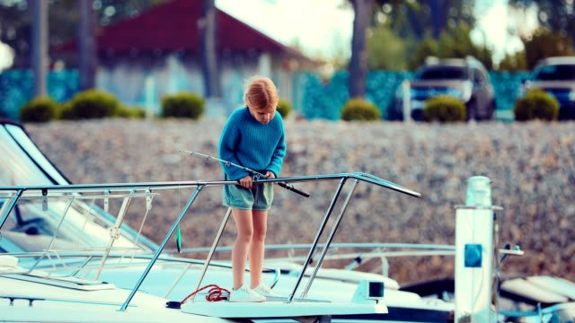 Mädchen-auf-einer-Yacht-oder-ein-Boot-besitzt-eine-Angelrute-und-befasst-sich-mit-einem-Fisch-Ort