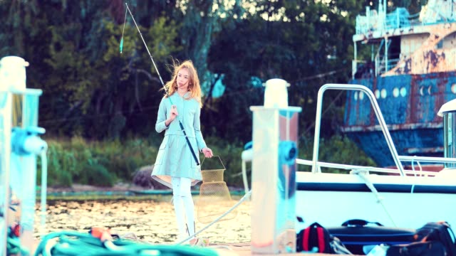 Girl-is-holding-a-fishing-rod-in-her-hands-and-posing-on-the-camera