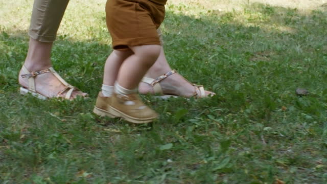 Beine-von-Mutter-und-Kind-zu-Fuß-auf-dem-Rasen