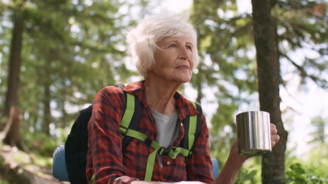 Senior-mujer-caminante-tomando-té-en-el-bosque