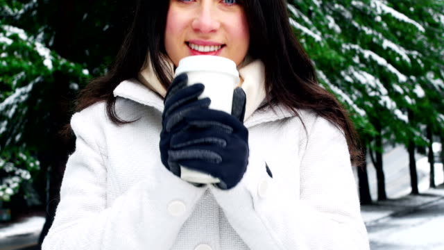 Lächelnde-Frau-in-warme-Kleidung-Kaffeetrinken-bei-Schneefall