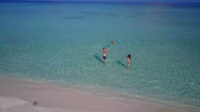 v03805-vista-aérea-de-drone-volador-de-playa-en-isla-paraíso-soleado-con-cielo-azul-aqua-mar-agua-océano-4k-2-personas-pareja-hombre-mujer-tocando-juntos-diversión-bola-blanco-Maldivas