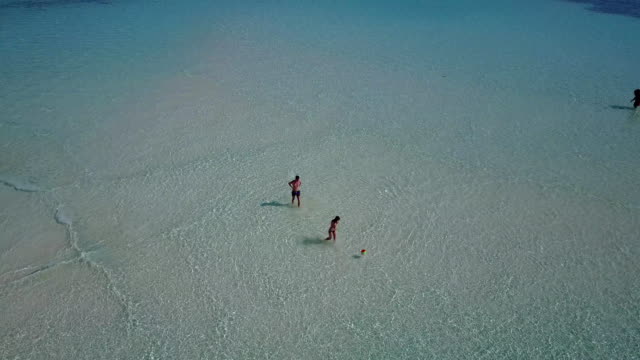 v03804-fliegenden-Drohne-Luftaufnahme-der-Malediven-weißen-Sandstrand-am-sonnigen-tropischen-Inselparadies-mit-Aqua-blau-Himmel-Meer-Wasser-Ozean-4k-2-Personen-junges-Paar-Mann-Frau-Ball-Spaß-zusammen-zu-spielen