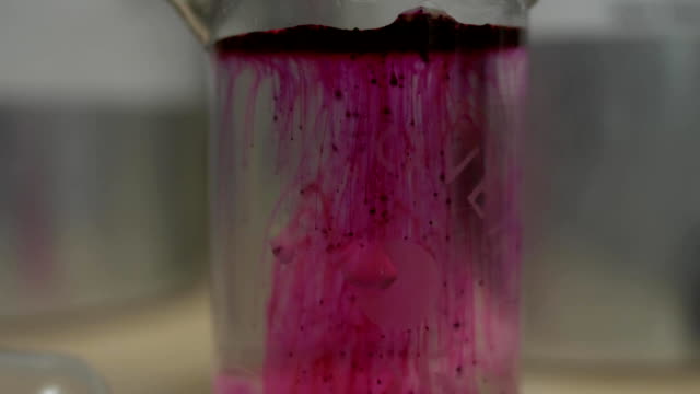 Nahaufnahme-des-Labor-Becher-mit-roten-Farbstoff-auflösen.-Rosa-oder-rote-Flüssigkeit-löst-sich-in-Flasche