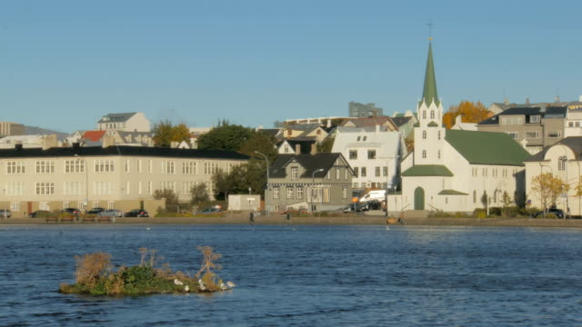 Blick-auf-alte-traditionelle-Gebäude-in-der-Nähe-von-Lake-Tjörnin-in-Reykjavik-im-sonnigen-Herbsttag
