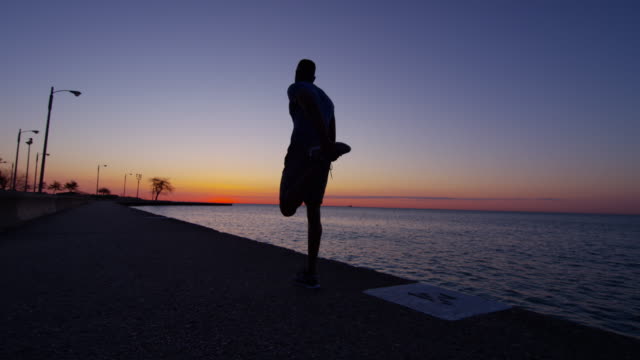 Ethnic-male-silhouette-at-sunrise-resting-after-workout