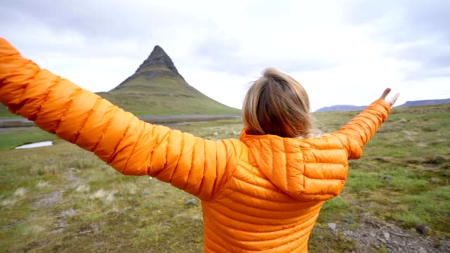 Young-woman-in-Iceland-arms-outstretched-for-freedom-Springtime-overcast-sky-at-famous-Kirkjufell-mountain