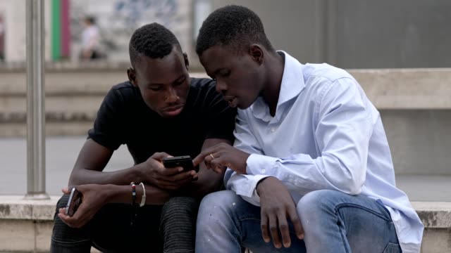 Dos-jóvenes-de-negro-africano-centrado-en-smartphone-en-la-calle
