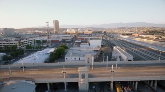 Toma-aérea-del-río,-carretera-y-edificios-en-el-centro-de-Los-Ángeles-durante-la-puesta-de-sol