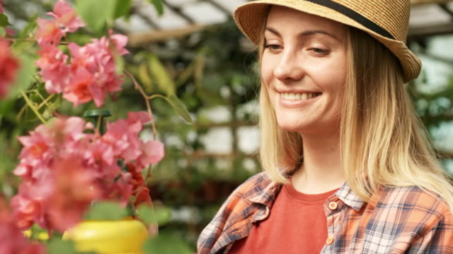 Mujer-alegre-cuidando-para-planta-de-flor-floreciente