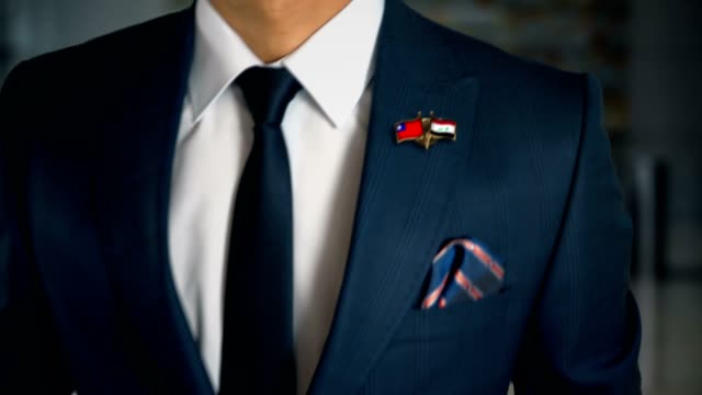 Businessman-Walking-Towards-Camera-With-Friend-Country-Flags-Pin-Taiwan---Iraq