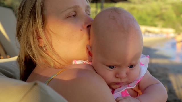 Loving-mother-kissing-baby-daughter-outdoor