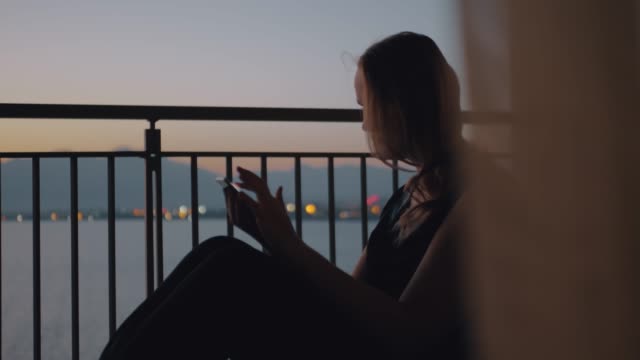 Frau-mit-Tablet-PC-auf-dem-Balkon-mit-Blick-auf-Meer