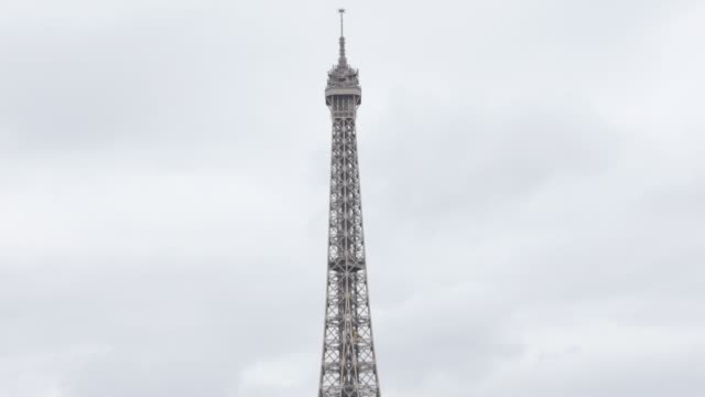 Slow-tilting-on-Eiffel-tower-and-symbol-of-France-in-front-of-cloudy-sky
