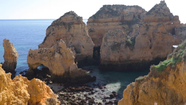 Ponta-da-Piedade,-Famous-place-in-south-Portugal,-Lagos-city,-The-rocky-coast,-waves-of-Atlantic-Ocean,-sharp-rocks,-azure-water,-yellow-flowers,-arch,-nobody,-wild-beach