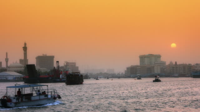 Locked-On-shot-of-a-ferry-boat-moving-on-river-at-dusk,-Dubai,-United-Arab-Emirates