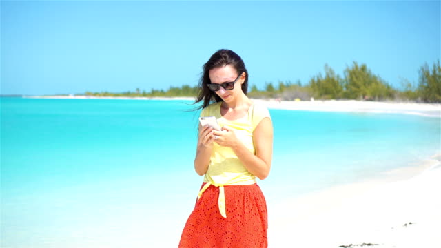 Young-woman-use-phone-during-tropical-beach-vacation.-Tourist-using-mobile-smartphone.