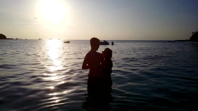 v04109-vuelo-drone-vista-aérea-de-Maldivas-playa-2-personas-pareja-hombre-mujer-amor-romántico-puesta-de-sol-salida-del-sol-en-la-isla-de-paraíso-tropical-soleado-con-cielo-azul-aqua-agua-mar-4k
