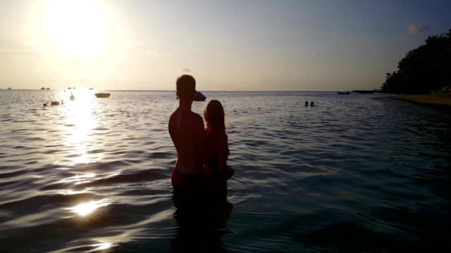 v04123-vuelo-drone-vista-aérea-de-Maldivas-playa-2-personas-pareja-hombre-mujer-amor-romántico-puesta-de-sol-salida-del-sol-en-la-isla-de-paraíso-tropical-soleado-con-cielo-azul-aqua-agua-mar-4k