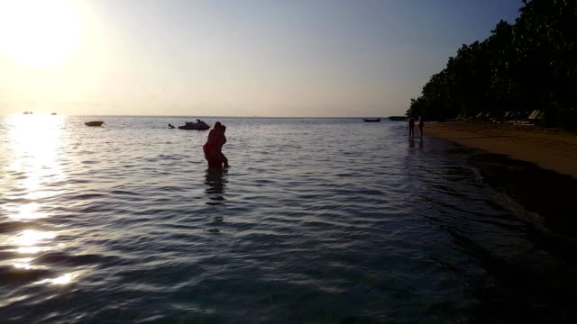 v04112-vuelo-drone-vista-aérea-de-Maldivas-playa-2-personas-pareja-hombre-mujer-amor-romántico-puesta-de-sol-salida-del-sol-en-la-isla-de-paraíso-tropical-soleado-con-cielo-azul-aqua-agua-mar-4k
