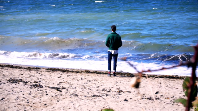 Hombre-de-pie-en-la-playa-en-un-día-soleado-4k