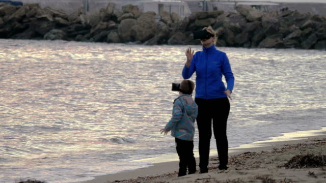 Mutter-und-Sohn-Spaß-mit-VR-Brille-am-Ufer