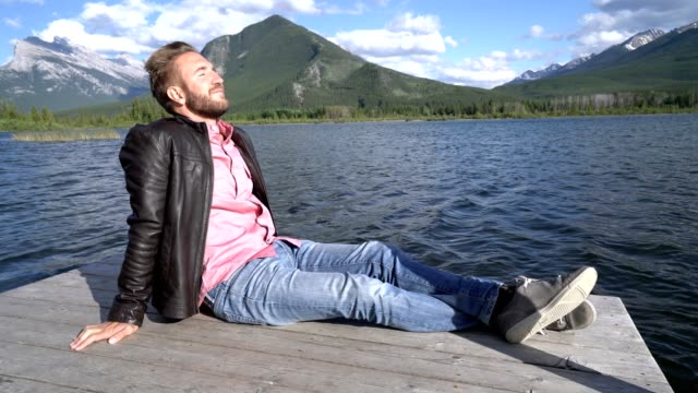 Hombre-contemplando-la-naturaleza-en-el-lago,-sentado-en-un-muelle-de-madera