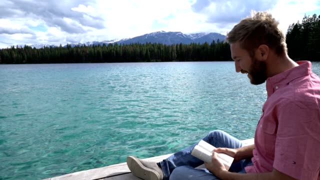Junger-Mann-auf-See-Pier-mit-Buch,-Kanada