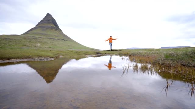 SLOW-MOTION-junge-Frau-in-Island-ausgestreckten-für-Freiheit-Frühling-bedecktem-Himmel-am-berühmten-Berg-Kirkjufell