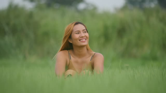 Woman-sitting-relaxing-with-arms-raised-in-the-grass-field