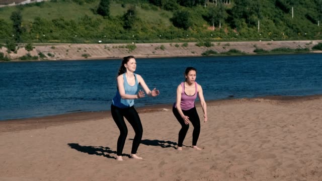 Dos-mujeres-haciendo-deportes-ejercicios-a-orillas-del-río-en-la-ciudad.-Saltar-desde-sentado.
