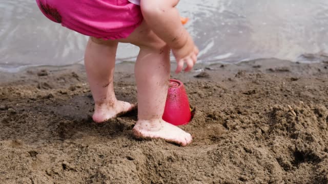 Kleines-Mädchen-klopft-eine-Paddel-auf-den-Eimer,-Slow-Motion.-Kind-spielt-auf-die-Natur-in-den-Sand-am-Strand