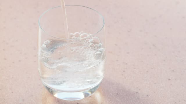 kohlensäurehaltigem-Mineralwasser-gießt-in-Glas