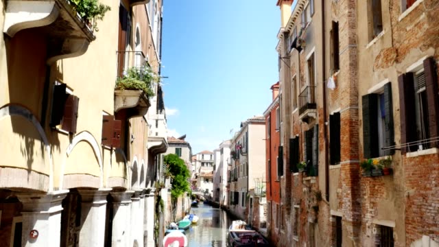 Venedig,-Italien---7.-Juli-2018:-schmalen-Kanal-zwischen-den-alten-Häusern-von-Venzia,-heißen-Sommertag