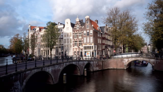 lapso-de-tiempo-de-día-de-barcos-en-canales,-puentes-y-edificios-de-apartamentos-en-amsterdam